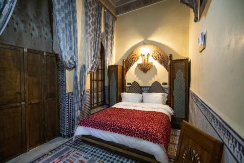 a bedroom with a bed with a red bedspread at Saphiryad in Fez