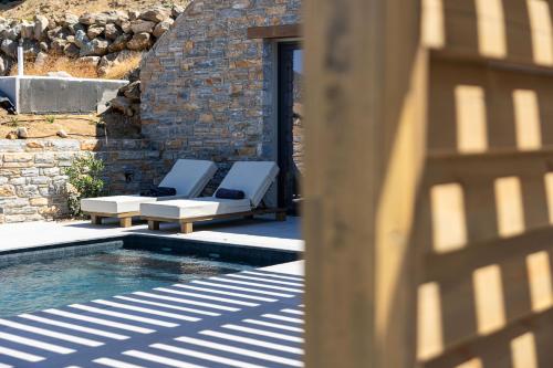 a pair of lounge chairs next to a swimming pool at Bonsai Luxury Villas Naxos in Naxos Chora