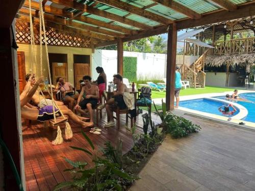 a group of people sitting on swings near a swimming pool at Liahs tortuguero in Tortuguero