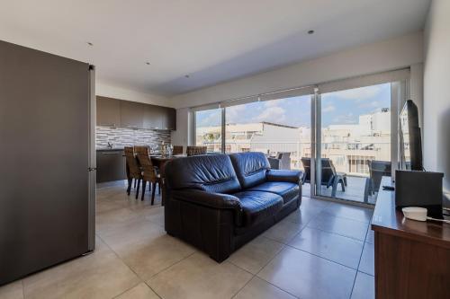 a living room with a blue leather couch and a kitchen at Bright and Spacious Penthouse with Large Terrace in Msida