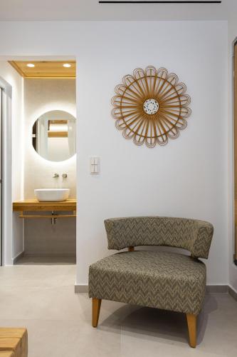 a bathroom with a chair and a sink and a mirror at Bonsai Luxury Villas Naxos in Naxos Chora