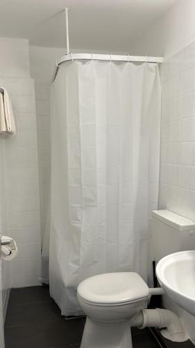 a white bathroom with a toilet and a sink at Art Rock Airport in Cologne