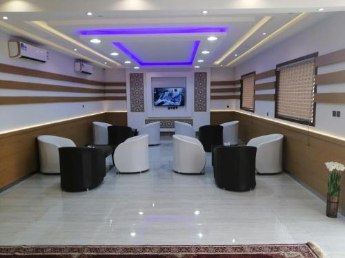 a waiting room with white chairs and a tv at برج الشارقة للشقق المخدومة in Najran
