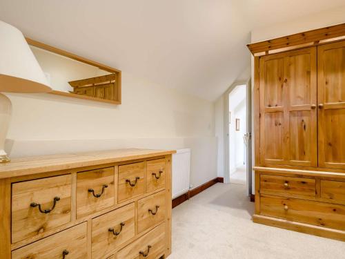 a kitchen with wooden cabinets and a dresser at 3 Bed in Bretforton 89477 in Bretforton