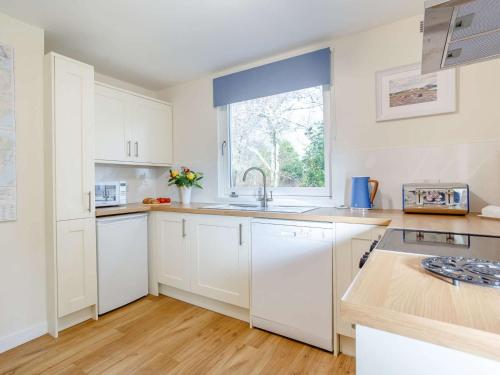 a kitchen with white cabinets and a sink and a window at 2 Bed in Camus Croise 86437 in Isleornsay
