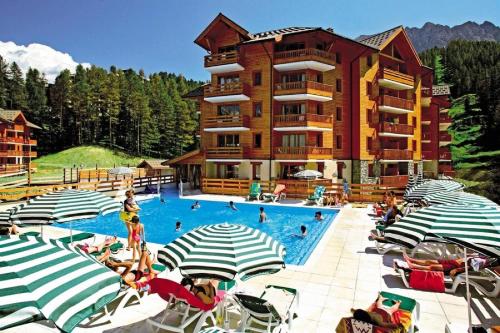 un grand hôtel doté d'une piscine avec des chaises et des parasols dans l'établissement Résidence L'Albane - maeva Home - Appartement 2 pièces 5 personnes Sélection MAE-7977, à Vars