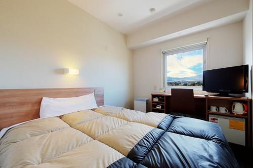 Schlafzimmer mit einem Bett, einem Schreibtisch und einem Fenster in der Unterkunft Super Hotel Gotemba Nigo-Kan in Gotemba