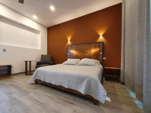 a bedroom with a large bed and a chair at Hotel Camino del Bosque Atlixco in Atlixco