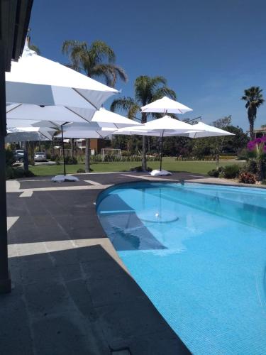 a swimming pool with white umbrellas and a swimming pool at Hotel Camino del Bosque Atlixco in Atlixco