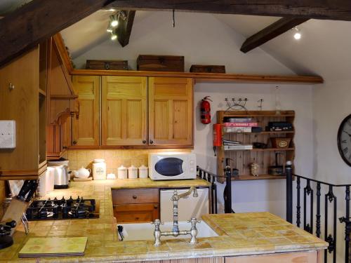 Una cocina con gabinetes de madera y microondas. en Mushroom Cottage, en Castleton
