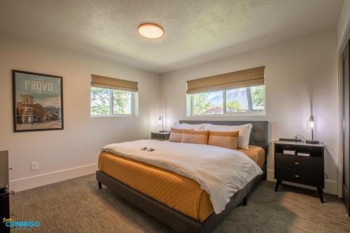 a bedroom with a large bed and two windows at Gathering Place Hot Tub Game rooms in Orem