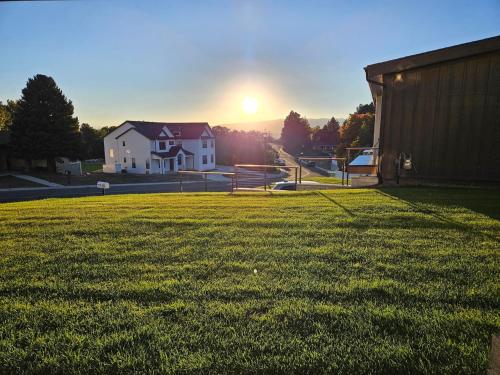 a house in a field with the sunset in the background at Gathering Place Hot Tub Game rooms in Orem