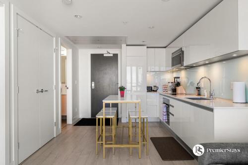 a kitchen with white cabinets and a table and chairs at Executive Suite on the 31st Floor Queen Bed with Sofa Bed Free Parking BBQ in Calgary