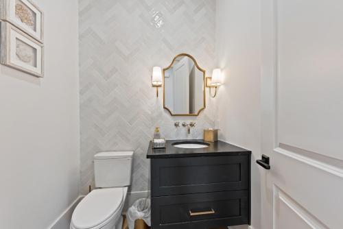 a bathroom with a toilet and a sink and a mirror at Stunning New Home with Private Pool in Seabrook Island