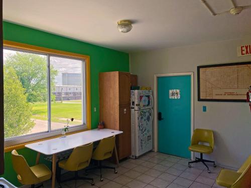 a kitchen with green walls and a table and a refrigerator at Hostel Detroit in Detroit