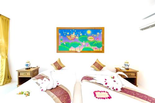 two beds in a room with a painting on the wall at Lamai Coconut Beach Resort in Lamai