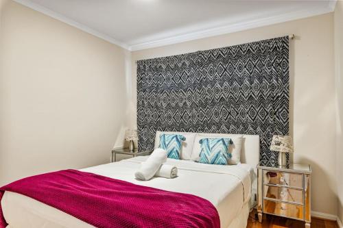 a bedroom with a large bed with a red blanket at Peaceful 4BR Retreat in Leafy Forest Lake Setting in Doolandella