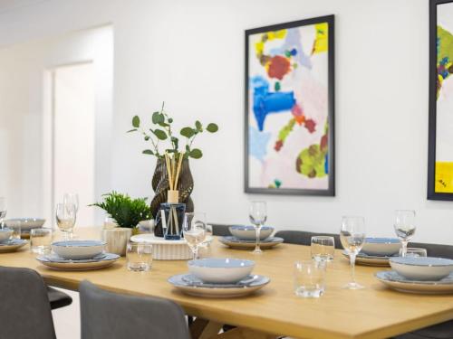 a wooden table with plates and glasses on it at Spacious Home 4BR Retreat with Pool in Parkinson in Browns Plains