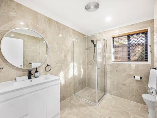 a bathroom with a shower and a sink and a mirror at Spacious Home 4BR Retreat with Pool in Parkinson in Browns Plains