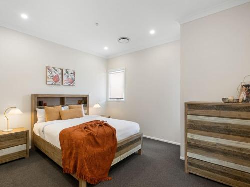 a bedroom with a large bed and a dresser at Spacious 4-Bedroom Bardon Retreat Across 2 Levels in Brisbane
