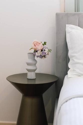 a vase with a pink rose on a table next to a bed at Spacious Family Retreat in Peaceful Parkinson in Browns Plains