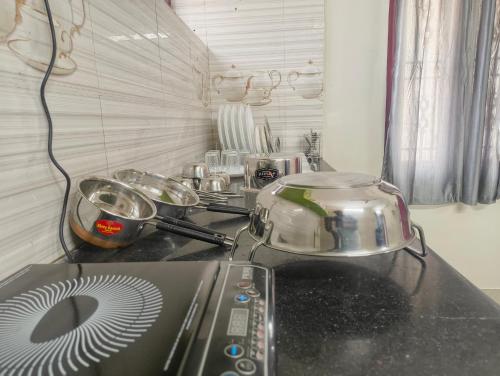 a kitchen counter with a stove with pots and pans at EESHA's Villa - Rameswaram in Rāmeswaram
