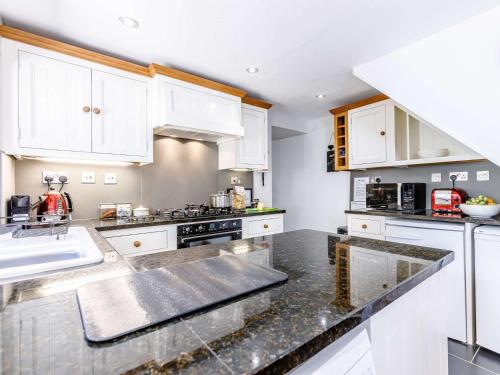 a kitchen with white cabinets and a black counter top at 3 Bed in Bourton-on-the-Water PTREE in Bourton on the Water