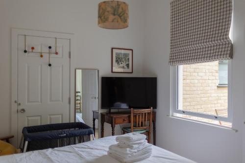 a bedroom with a bed and a desk and a television at Lin Song House South London Garden Room Getaway in London