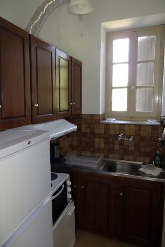a kitchen with wooden cabinets and a sink and a window at Tsorni Hill Cottage in Lefokastro