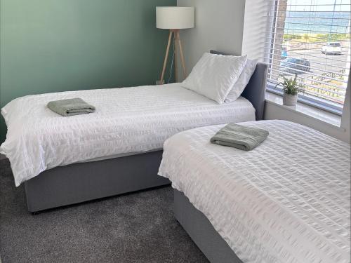 a bedroom with two beds and a window at Glenholme Apartment 1 in Redcar