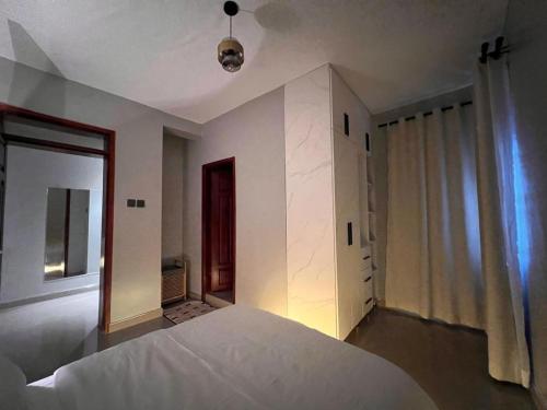 a bedroom with a white bed and a mirror at Home2Suite by Veronica Bunga-Buziga-Munyonyo- Luxury with Netflix, DStv, Wi-Fi, & Free Parking in Kampala