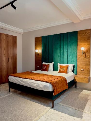 a bedroom with a large bed with a green wall at Mondo suites apparts Tunis lac 2 in Tunis