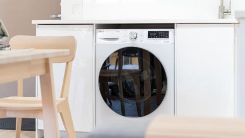 a washing machine in a kitchen next to a table at White Dunes in Pervalka