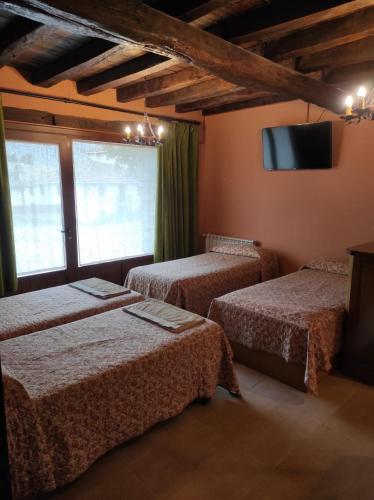 a room with three beds and a flat screen tv at Sagardikoetxea HABITACIONES CON BAÑO EN CASA RURAL in Oskotz