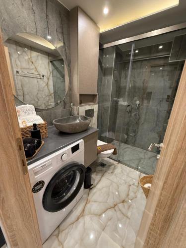 y baño con lavadora y ducha. en Hellenikon Suites Malama, en Paralia Katerinis