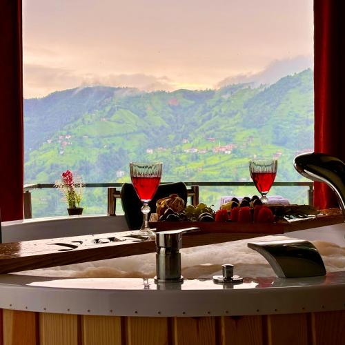 a table with wine glasses and a view of a mountain at Yaylamisun Suite Otel in Çamlıhemşin