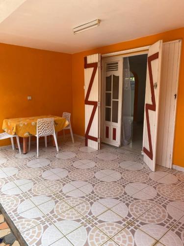 a room with a table and a room with orange walls at Maison charmante à Baie-Mahault avec jardin clôturé in Baie-Mahault