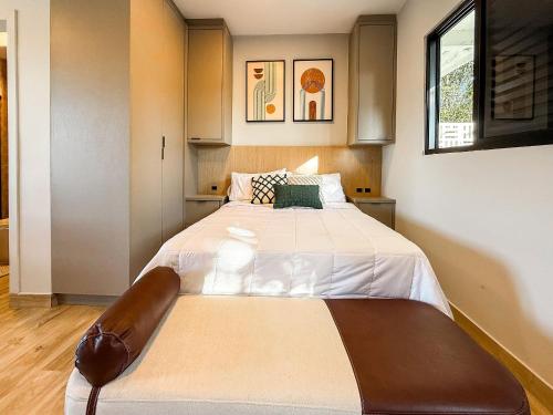 a bedroom with a large bed with white sheets at Seu Refúgio Urbano em Criciúma – Lago di Garda Studios in Criciúma