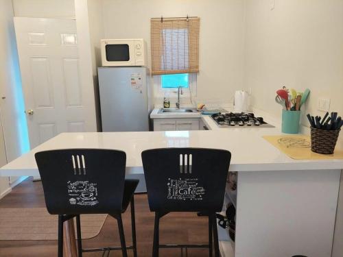 a kitchen with a white counter and two chairs at Lindas y acogedoras cabañas en puerto varas. in Puerto Chico
