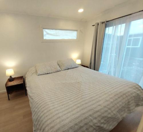 a bedroom with a large bed and a window at Lindas y acogedoras cabañas en puerto varas. in Puerto Chico