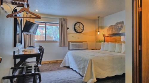 a bedroom with a bed and a clock on the wall at Yellowstone Village Inn and Suites in Gardiner