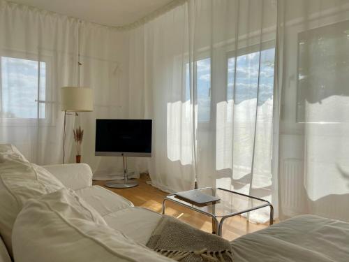 un salon blanc avec un canapé et une télévision dans l'établissement Designerwohnung mit malerischer Terrasse - Modern, Gemütlich & Zentral, à Hochheim am Main