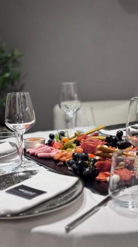 a table with a plate of food and wine glasses at ALYACHT Premium Hotel in Sarandë