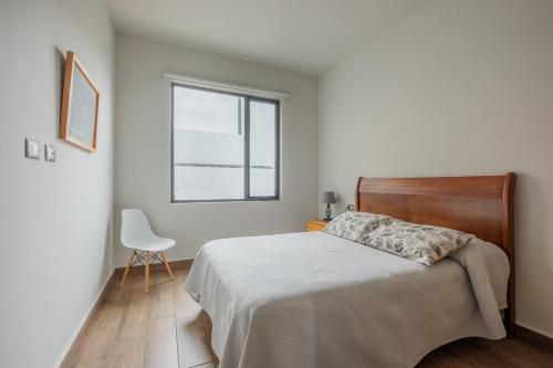 a bedroom with a bed and a chair and a window at Olivia's home in Zibata Queretaro in La Cañada