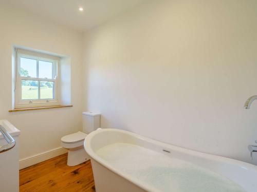 a white bathroom with a tub and a toilet at 3 bed property in Pooley Bridge 85362 in Pooley Bridge
