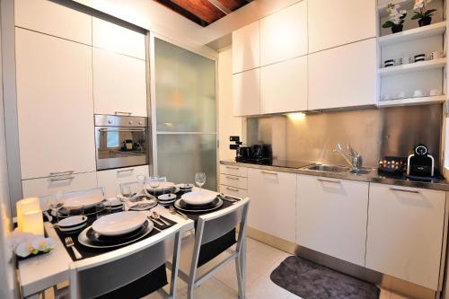 a kitchen with white cabinets and a table with chairs at Palazzo del Sale, Rialto in Venice