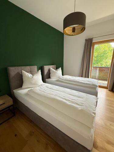 two beds in a room with a green wall at Bestezeit Appartements in Schladming