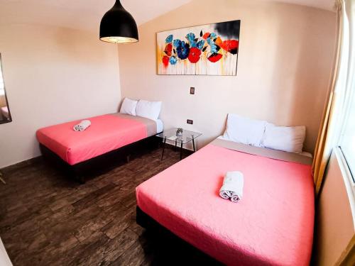 two beds in a room with red sheets at Estancia luxury central, Paseo Durango in Durango