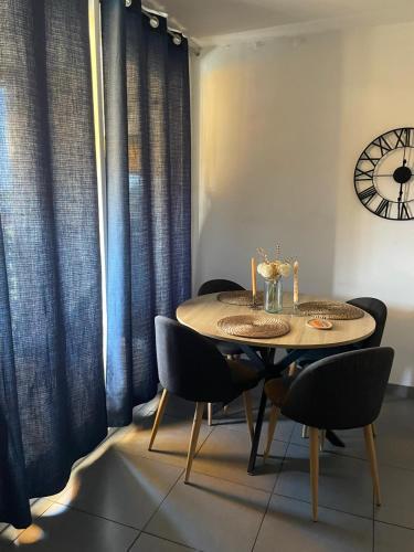 a dining room table with chairs and a clock on the wall at Cocon du Jaï in Marignane
