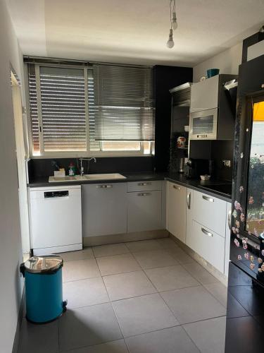 a kitchen with white cabinets and a large window at Cocon du Jaï in Marignane